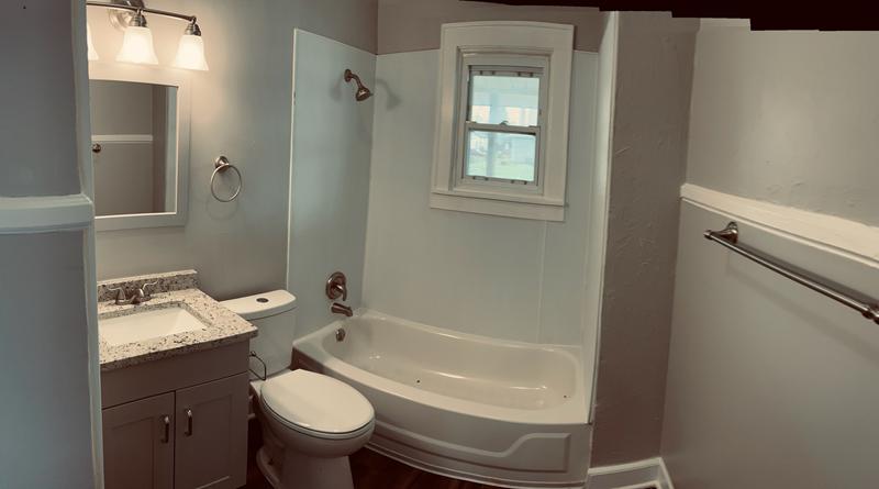 Updated bathroom with a new vanity, tub surround and light fixture