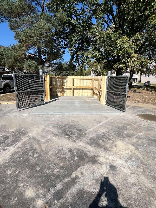 Finished concrete pad and wood dumpster enclosure with gates