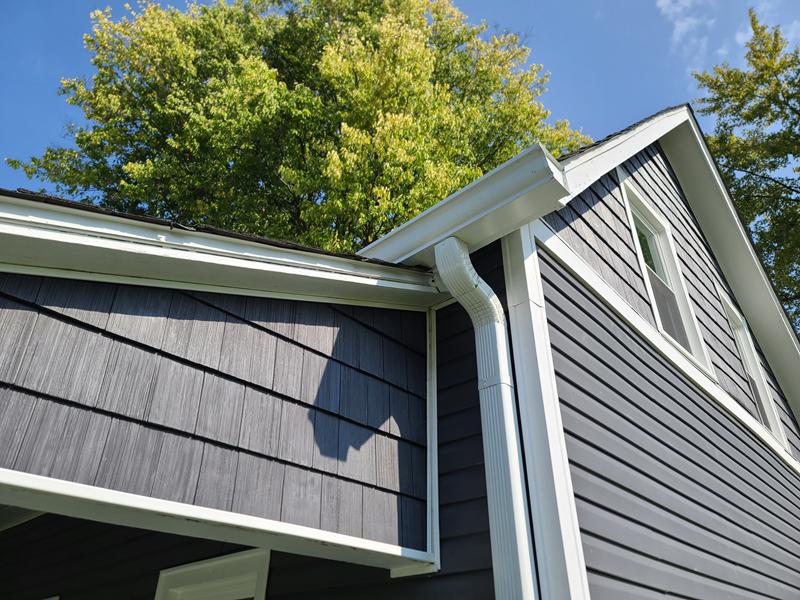 New white gutters and downspout below a shingle roof