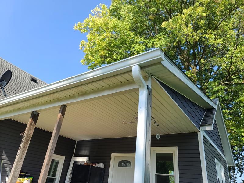 New white seamless gutter and downspout along a porch roof