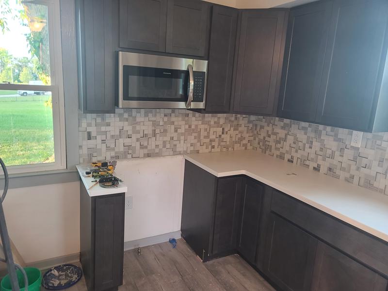 Remodeled kitchen with dark shaker cabinets, white counters and a mosaic tile backsplash