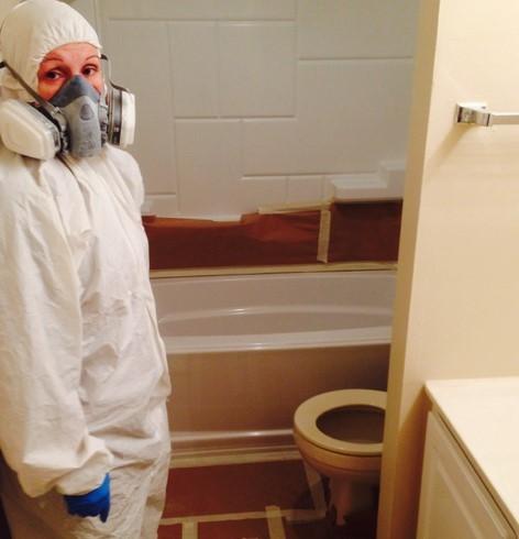 Crew member in a protective suit and respirator working in a bathroom