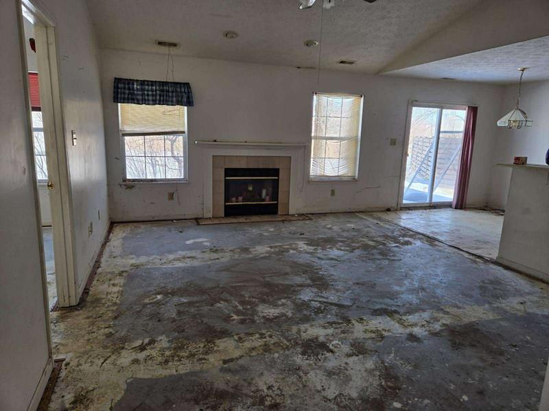 Living room with old flooring removed and a stained subfloor, before the remodel