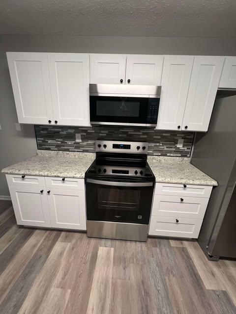 New kitchen with white cabinets, range and vinyl plank floor